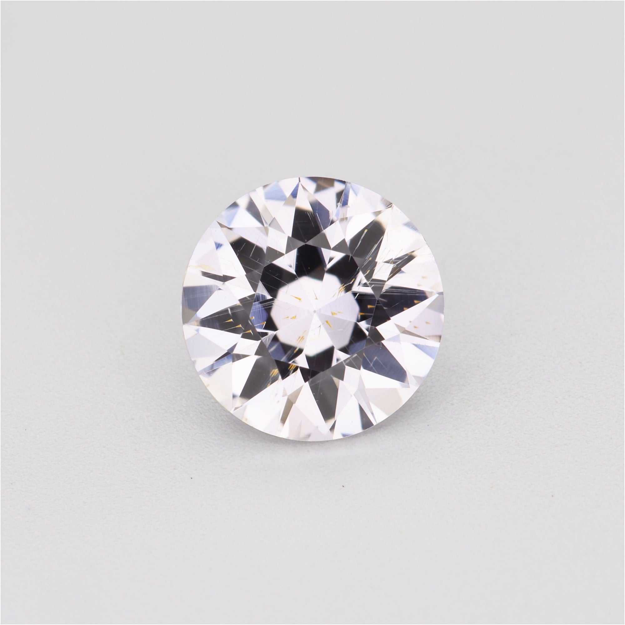 1.30 ct round white sapphire with faint peach tint showing brilliance and clarity