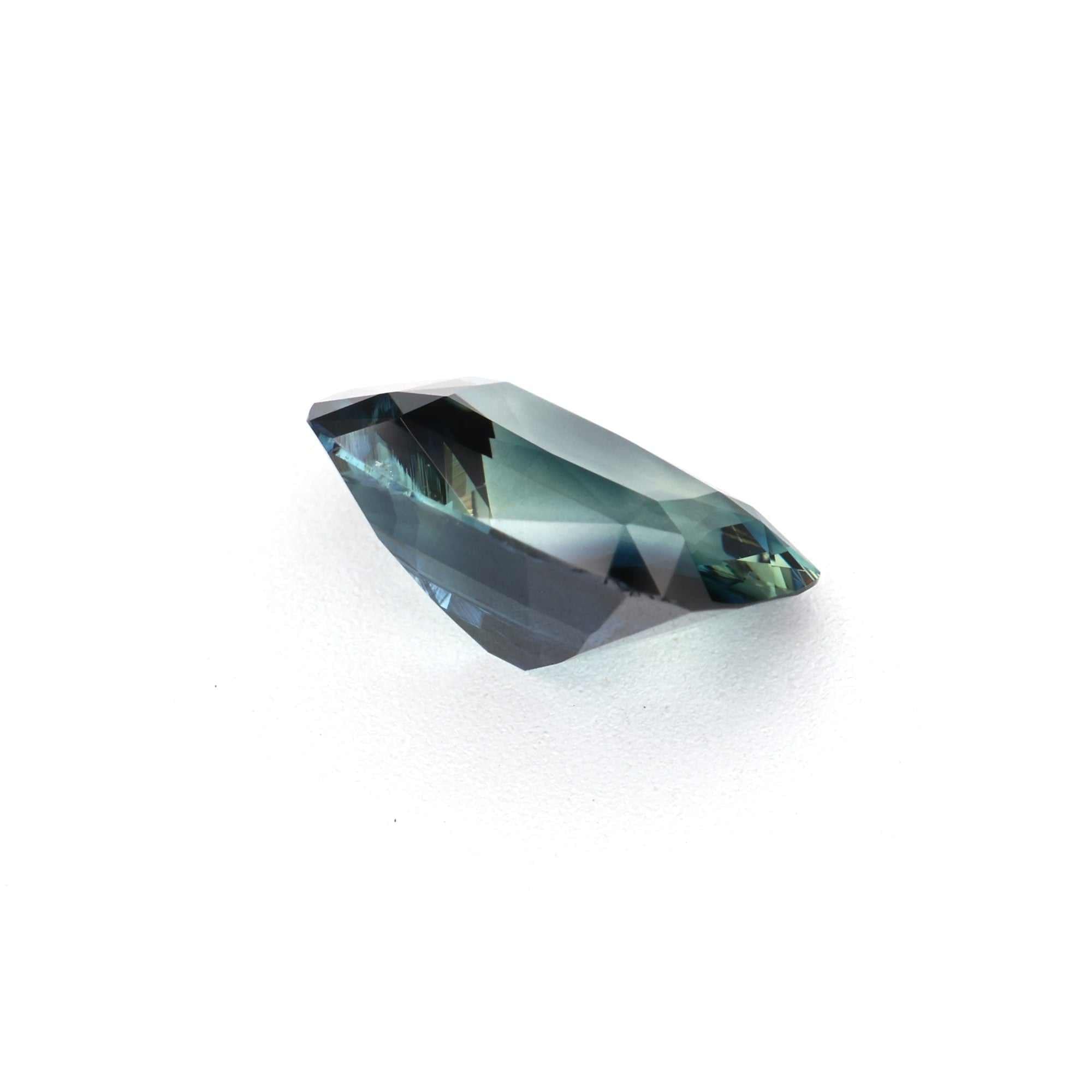 1.30 ct unheated teal sapphire on white background showing blue-green hue and transparency