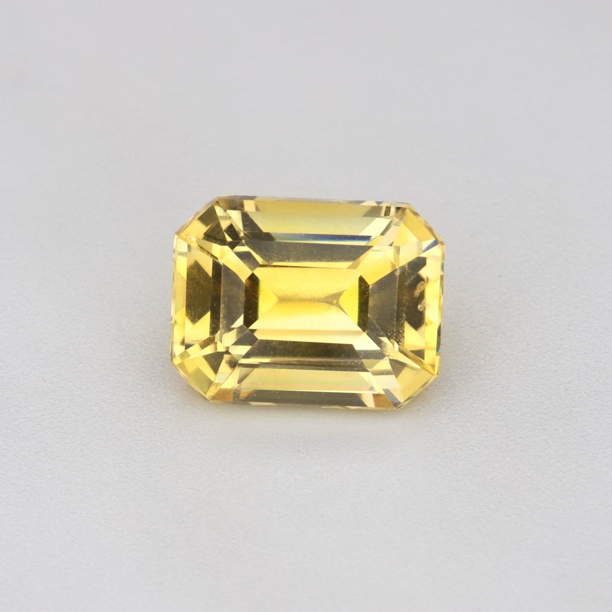 1.17 ct Emerald-Cut Ceylon Yellow Sapphire displayed on a neutral background, showcasing its vibrant golden hue.