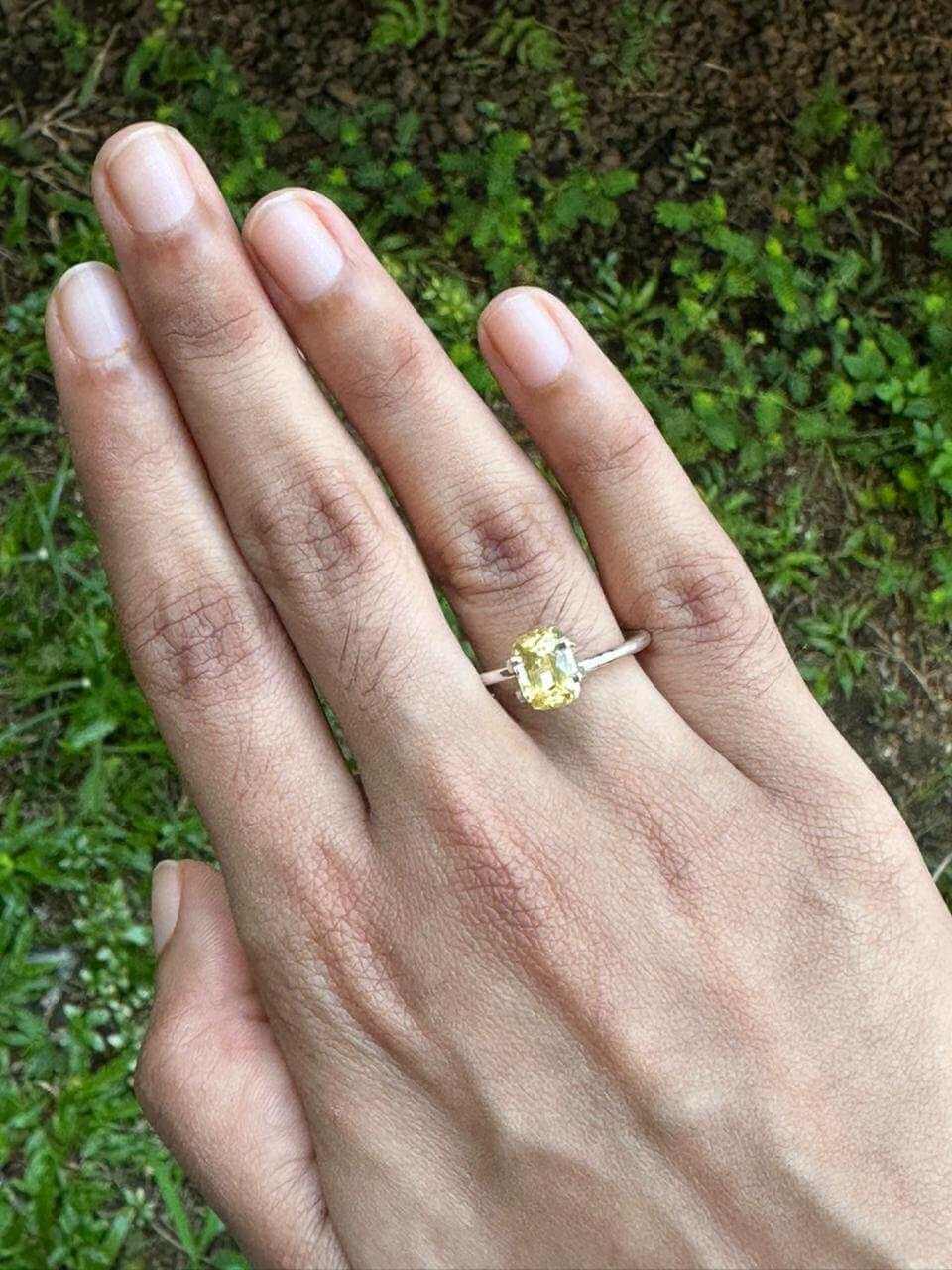 A hand wearing a ring featuring a 2.175 ct Cushion Yellow Sapphire set in a simple band.