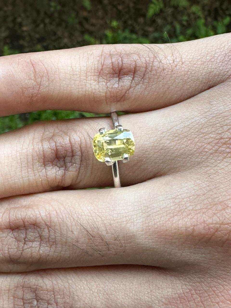 2.175 ct Cushion Yellow Sapphire set on a silver ring, displaying its golden hue on a hand.