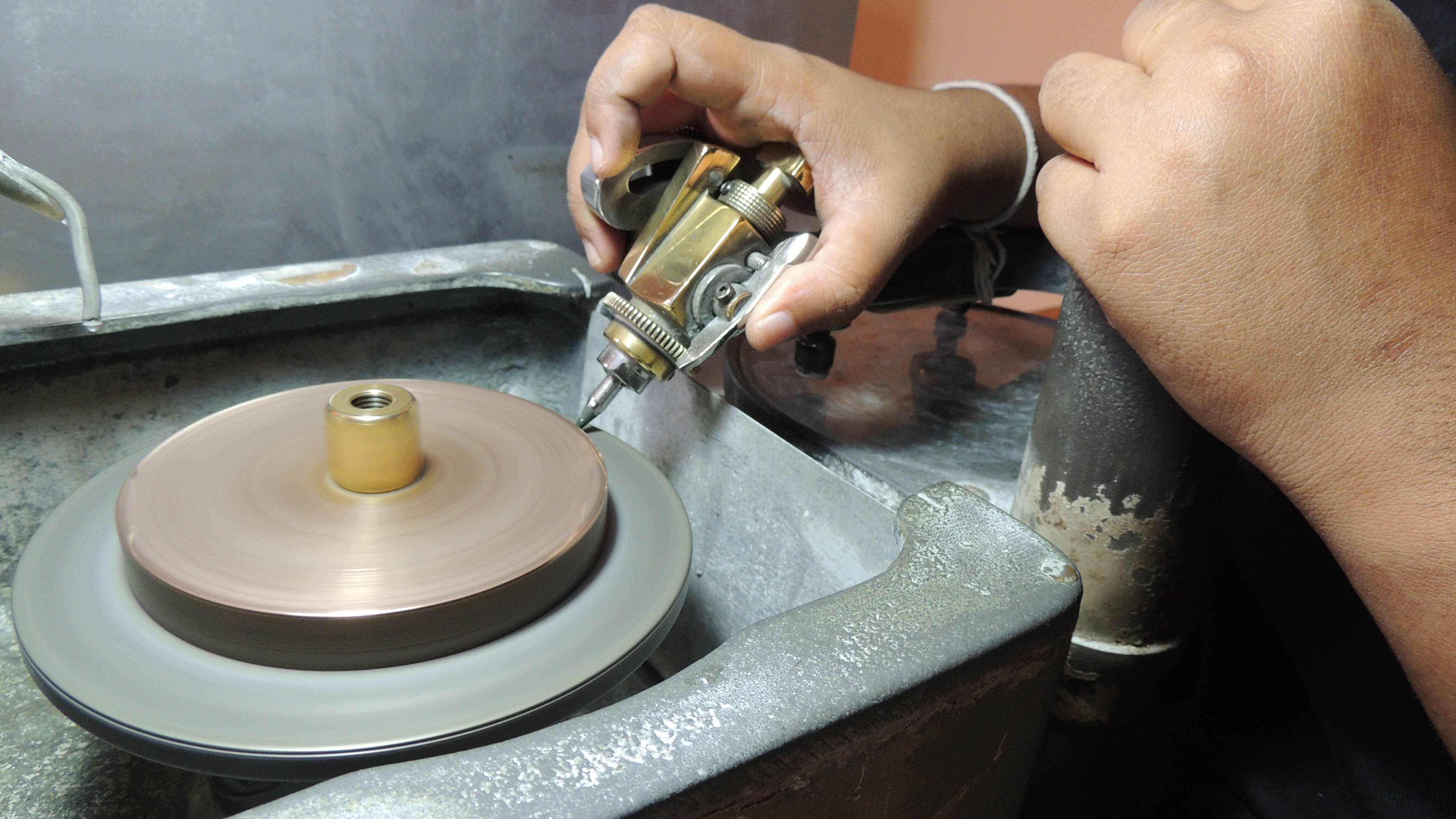 Close-up of a sapphire gemstone being faceted on a precision faceting machine showing detailed facets and angle adjustments