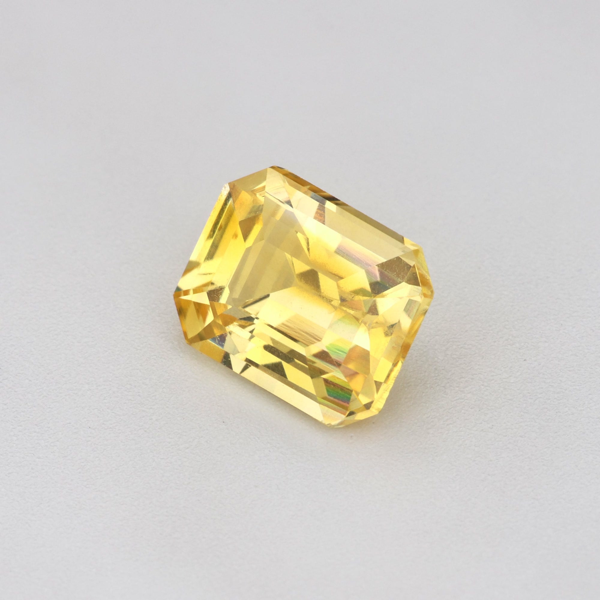 1.17 ct Emerald-Cut Ceylon Yellow Sapphire on a gray background, showcasing its heat-treated golden hue.