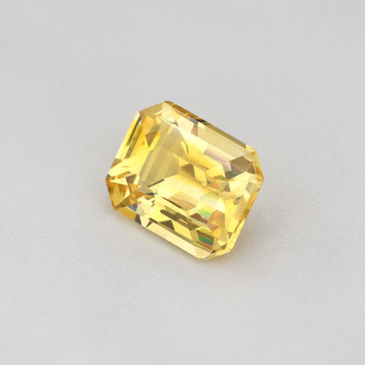 1.17 ct Emerald-Cut Ceylon Yellow Sapphire on a gray background, showcasing its heat-treated golden hue.