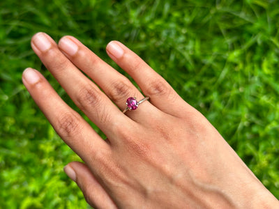 1.65 ct unheated Oval Ruby ring showcased on a hand against a lush green background, highlighting its vibrant color and setting.