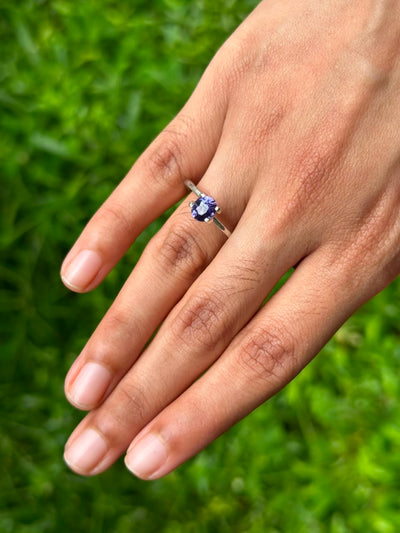 1.20 ct Oval Purple Sapphire set in a ring, showcased on a hand against a grassy background.