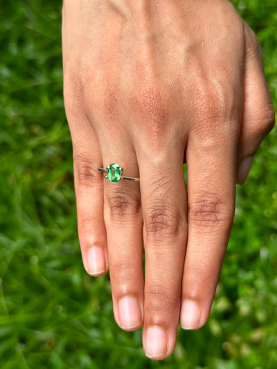 1.06 ct Cushion Tsavorite Garnet ring displayed on a hand with a green grass background.