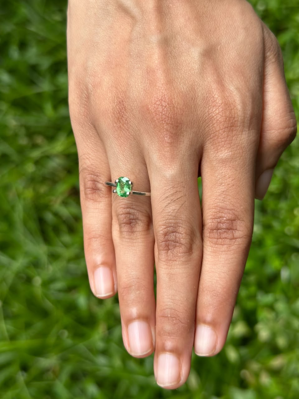 1.06 ct Cushion Tsavorite Garnet ring displayed on a hand with a green grass background.