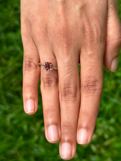 1.62 ct Emerald-Cut Brown Sapphire ring displayed on a hand in a grassy setting.
