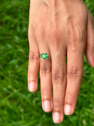 1.79 ct Round Tsavorite Garnet ring displayed on a hand, set against a green grass background.