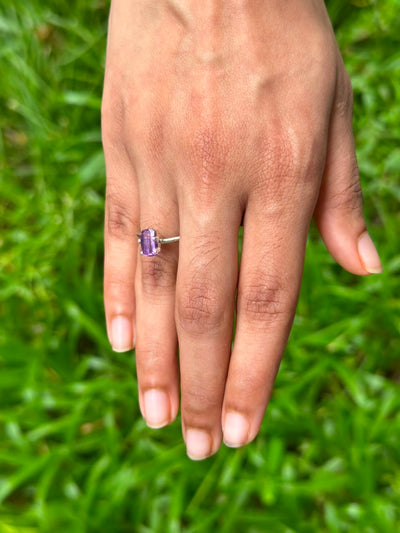 1.45 ct Natural Heat-Treated Purple Sapphire set in a ring worn on a hand, showcasing its elegant design against a green background.