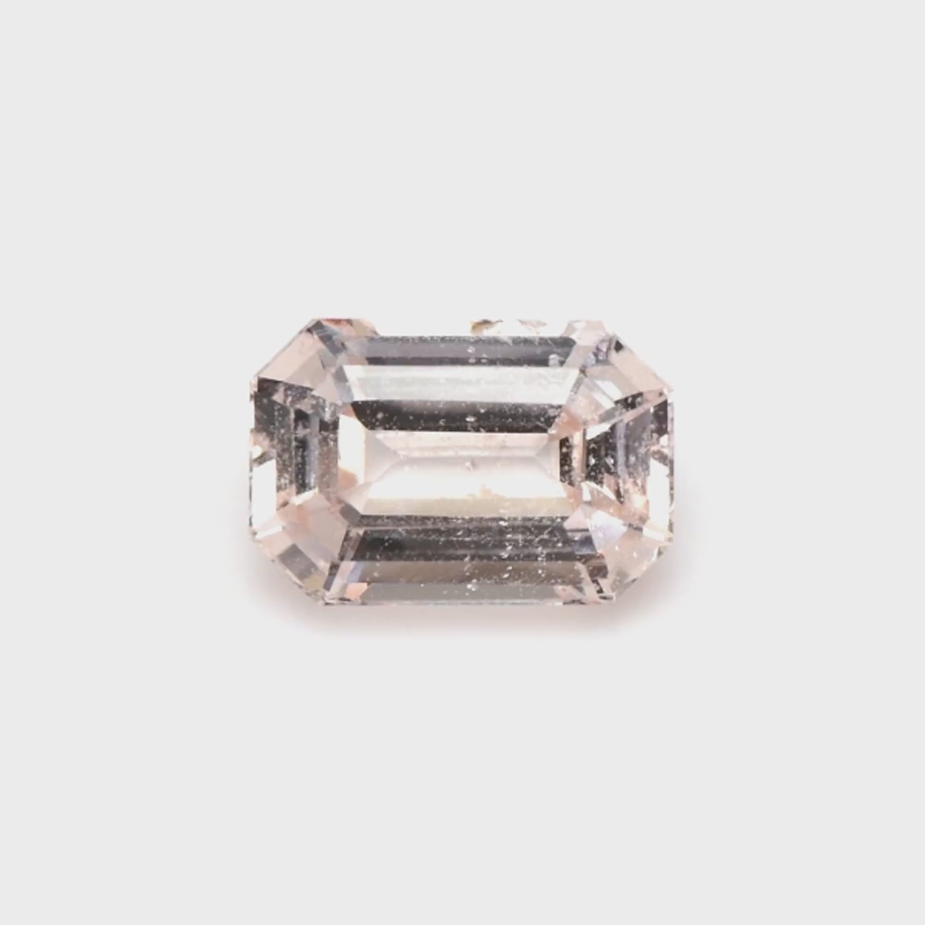 1.50 ct emerald cut peach sapphire rotating to show warm peach color and brilliance